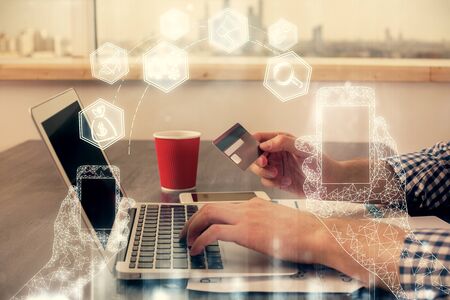 Double exposure of man hands holding a credit card and tech theme drawing. Technology in E-commerce concept.の写真素材