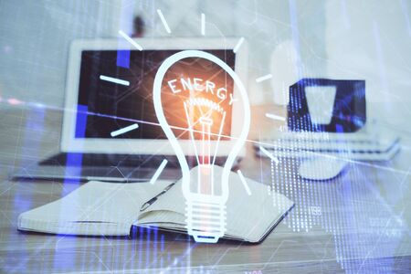 Computer on desktop in office with bulb icon hologram. Multi exposure. Concept of idea.の写真素材