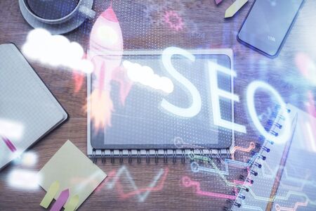 Double exposure of SEO hologram drawing over desktop. Top view. Search optimization concept.の写真素材
