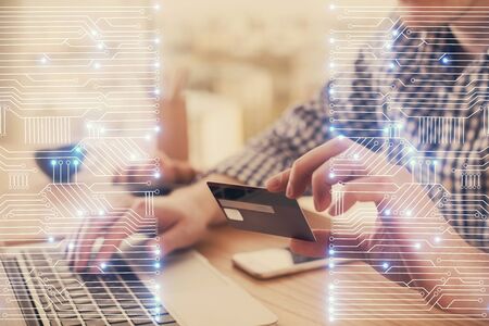 Double exposure of man hands holding a credit card and tech theme drawing. Technology in E-commerce...