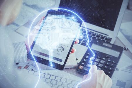 Double exposure of mans hand holding and using a digital device and brain hologram drawing. Data...