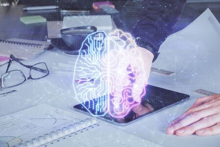 Double exposure of mans hand holding and using a digital device and brain hologram drawing. Data...