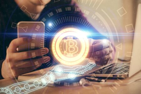 Double exposure of mans hands holding and using a phone and crypto currency blockchain theme...