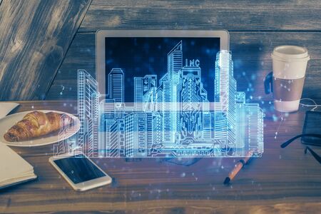 Desktop computer background in office and big town buildings hologram drawing. Double exposure. Smart city concept.の写真素材