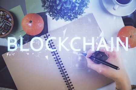 Cryptocurrency hologram over woman's hands writing background. Concept of blockchain. Multi exposureの写真素材