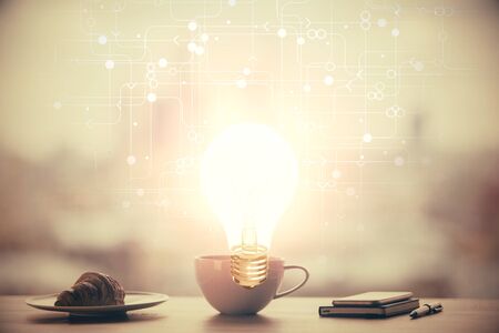 Double exposure of light bulb hologram over coffee cup background in office. Concept of ideaの写真素材