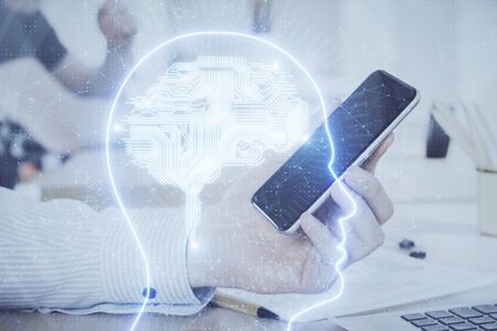 Double exposure of mans hand holding and using a digital device and brain hologram drawing. Data concept.の写真素材