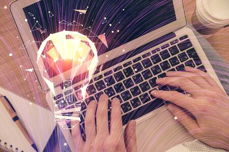 Double exposure of man's hands typing over computer keyboard and bulb hologram drawing. Top view. Idea concept.の写真素材