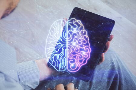 Double exposure of mans hand holding and using a digital device and brain hologram drawing. Data concept.の写真素材