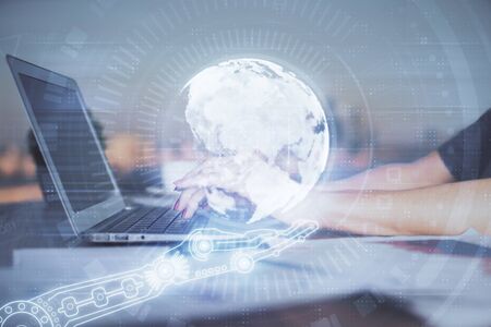 Double exposure of woman hands working on computer and world map hologram drawing. International...