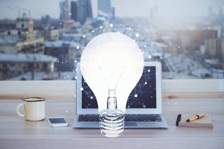 Computer on desktop in office with bulb icon hologram. Multi exposure. Concept of idea.の写真素材
