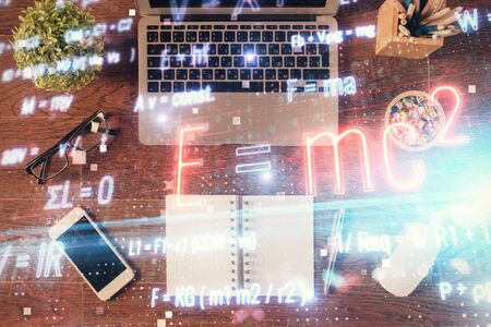 Physics and math theme hologram with formula drawings over computer on the desktop background. Top view. Multi exposure. Concept of education.の写真素材