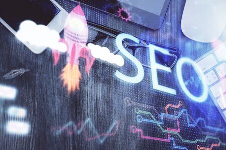 Double exposure of SEO hologram drawing over desktop. Top view. Search optimization concept.の写真素材