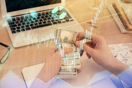 Multi exposure of financial graph drawing hologram and USA dollars bills and man hands. Analysis concept.の写真素材