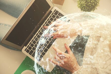 Double exposure of woman hands working on computer and social network theme hologram drawing. Top...