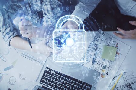 Double exposure of lock hologram drawing and man and woman working together holding and using a mobile device. Security concept.の写真素材