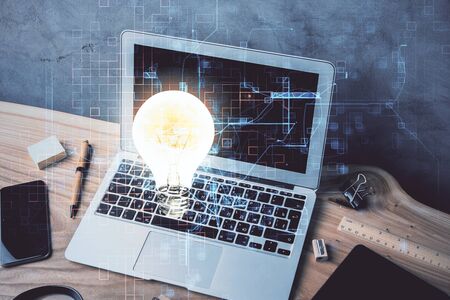 Computer on desktop in office with bulb icon hologram. Multi exposure. Concept of idea.の写真素材