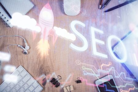 Double exposure of SEO hologram drawing over desktop. Top view. Search optimization concept.の写真素材