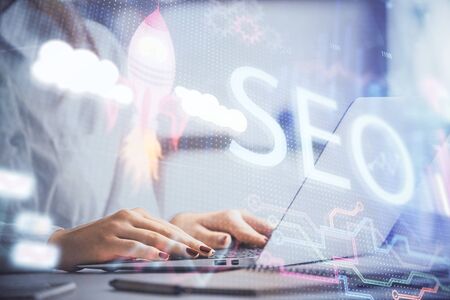 Double exposure of woman hands working on computer and seo hologram drawing. internet search concept.の写真素材