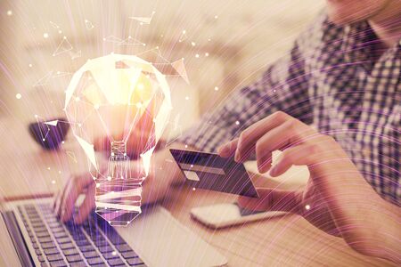 Double exposure of man hands holding a credit card and bulb drawing. Idea E-commerce concept.の写真素材