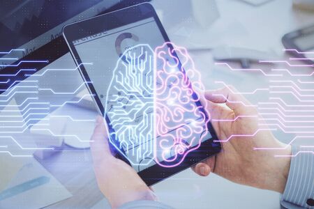 Double exposure of mans hand holding and using a digital device and brain hologram drawing. Data...