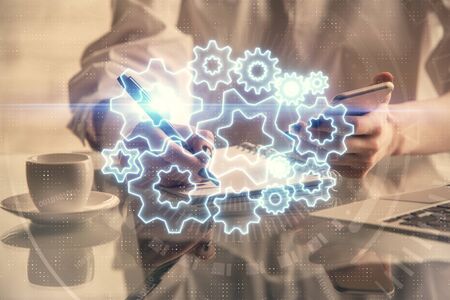Double exposure of business theme sketch hologram and woman holding and using a mobile device.