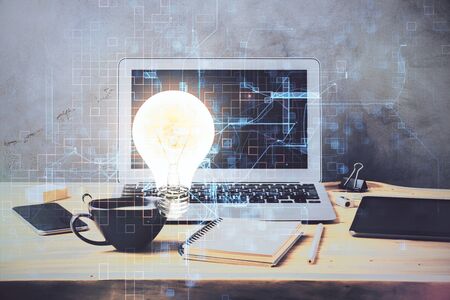 Computer on desktop in office with bulb icon hologram. Multi exposure. Concept of idea.の写真素材