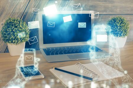 Desktop computer background in office and flying envelops hologram drawing. Multi exposure. Electronic mail concept.の写真素材