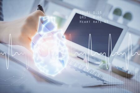 Heart hologram over woman's hands writing background. Concept of Medical study. Multi exposureの写真素材