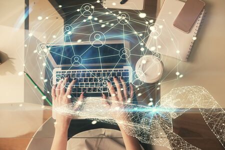 Double exposure of woman hands working on computer and social network theme hologram drawing. Top...