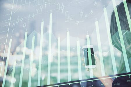 Double exposure of forex chart sketch hologram and woman holding and using a mobile device. Stock...
