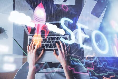 Double exposure of woman hands working on computer and SEO hologram drawing. Top View. Search optimization concept.の写真素材