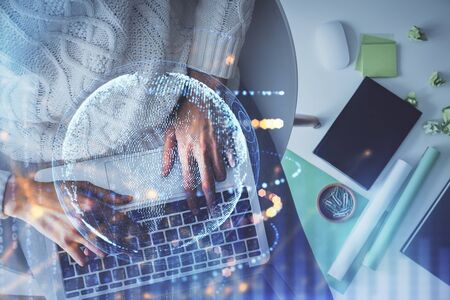 Double exposure of woman hands working on computer and world map hologram drawing. Top View....