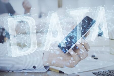 Double exposure of mans hand holding and using a digital device and data theme hologram drawing....