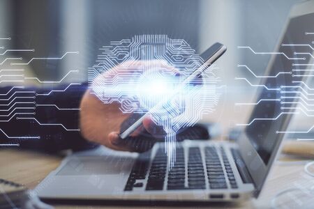 Double exposure of mans hand holding and using a digital device and brain hologram drawing. Data...