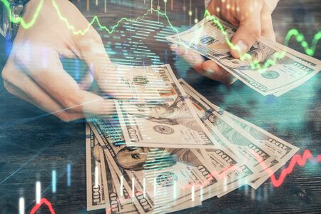 Multi exposure of financial graph drawing hologram and USA dollars bills and man hands. Analysis...