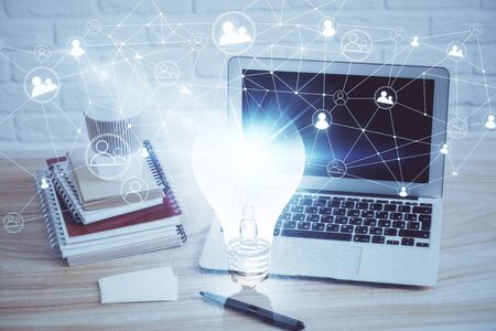 Computer on desktop in office with bulb icon hologram. Multi exposure. Concept of idea.の写真素材