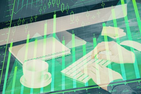 Multi exposure of graph with man typing on computer in office on background. Concept of hard work.の写真素材