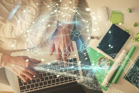 Double exposure of woman hands working on computer and social network theme hologram drawing. Top...