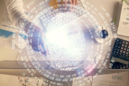 Double exposure of mans hands typing over computer keyboard and finger print hologram drawing. Top...