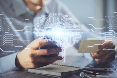 Double exposure of mans hand holding and using a digital device and brain hologram drawing. Data...