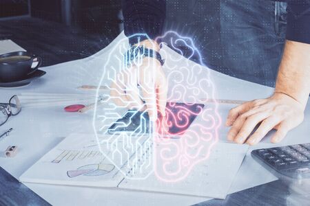 Double exposure of mans hand holding and using a digital device and brain hologram drawing. Data concept.の写真素材