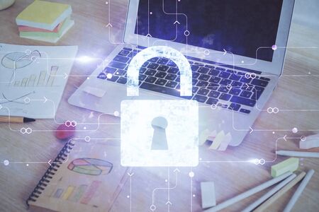 Double exposure of desktop with computer and lock icon hologram. Concept of data safety.