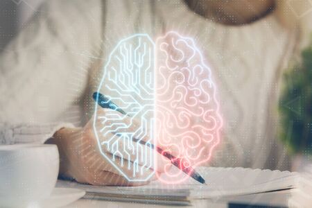 Multi exposure of writing hand on background with brain hologram. Concept of learning.の写真素材