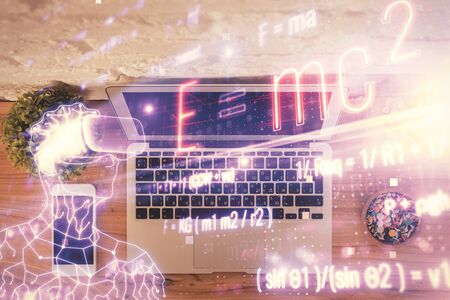 Physics and math theme hologram with formula drawings over computer on the desktop background. Top view. Multi exposure. Concept of education.の写真素材