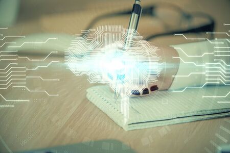 Multi exposure of woman's writing hand on background with brain hologram. Concept of brainstorming.の写真素材