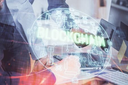 Crypto currency theme hologram with businessman working on computer on background. Concept of blockchain. Multi exposure.の写真素材