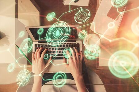 Double exposure of woman hands working on computer and social network theme hologram drawing. Top...