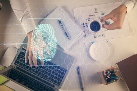 Double exposure of mans hands typing over computer keyboard and finger print hologram drawing. Top view. Personal security concept.の写真素材