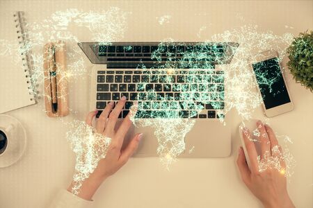Double exposure of woman hands working on computer and social network theme hologram drawing. Top...